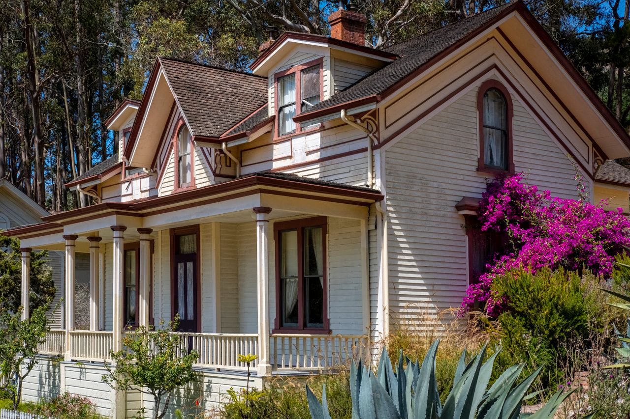 services-03 Beautiful Victorian house surrounded by vibrant gardens and trees, perfect for architecture and nature lovers.