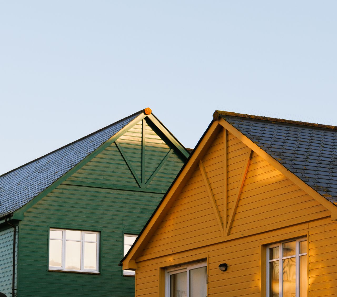 services-bg Green and yellow wooden house roofs under clear sky at sunset.