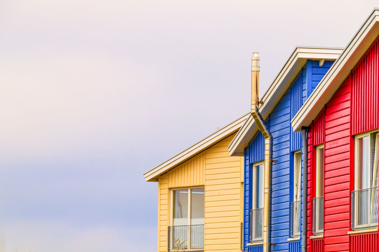 Vibrant red, blue, and yellow modern houses with clear sky backdrop, highlighting minimalist architecture.